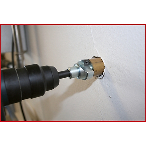 Bohrmaschine bohrt in eine Wand. Bohrer in der Wand, Metallmanschette am Bohrer.